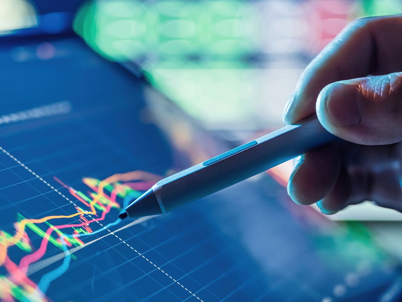 Close-up of a person pointing a stylus at a screen displaying a line graph